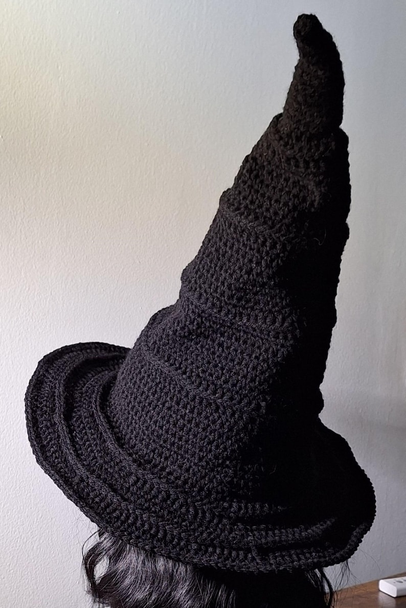 May include: A black crocheted witch hat with a tall, pointed crown and a wide brim.