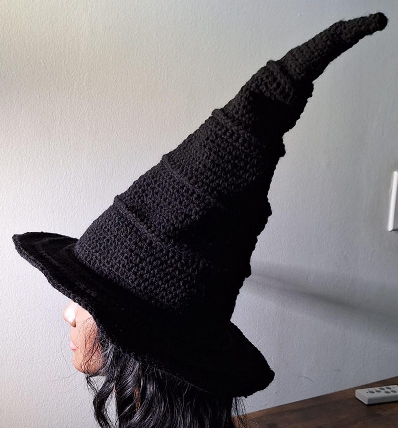May include: A black crocheted witch hat with a tall, pointed crown and a wide brim.