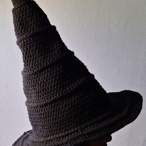 May include: A black crocheted witch hat with a tall, pointed crown and a wide brim.