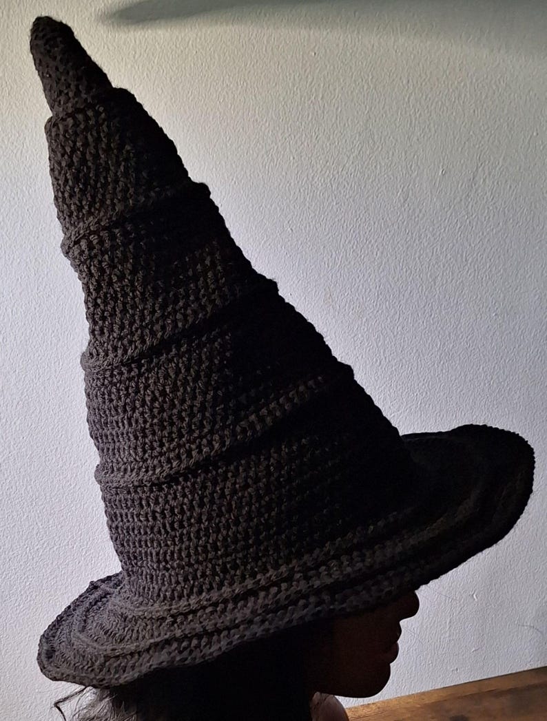 May include: A black crocheted witch hat with a tall, pointed crown and a wide brim.