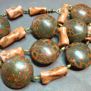 May include: A necklace made of colorful patterned round beads and brown cylindrical beads. The beads are strung on a gold chain.