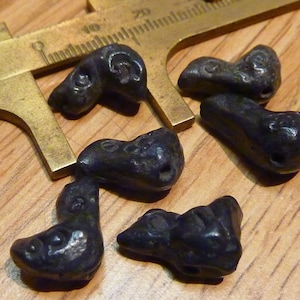 May include: Five black metal beads with intricate designs, possibly from an ancient civilisation. The beads are being measured with a caliper.