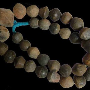 May include: A string of brown clay beads, some with a textured surface, connected by a turquoise cord.