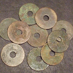 May include: A collection of ten copper coins with a hole in the center. The coins have different designs, including a star and the words "ONE PENNY".