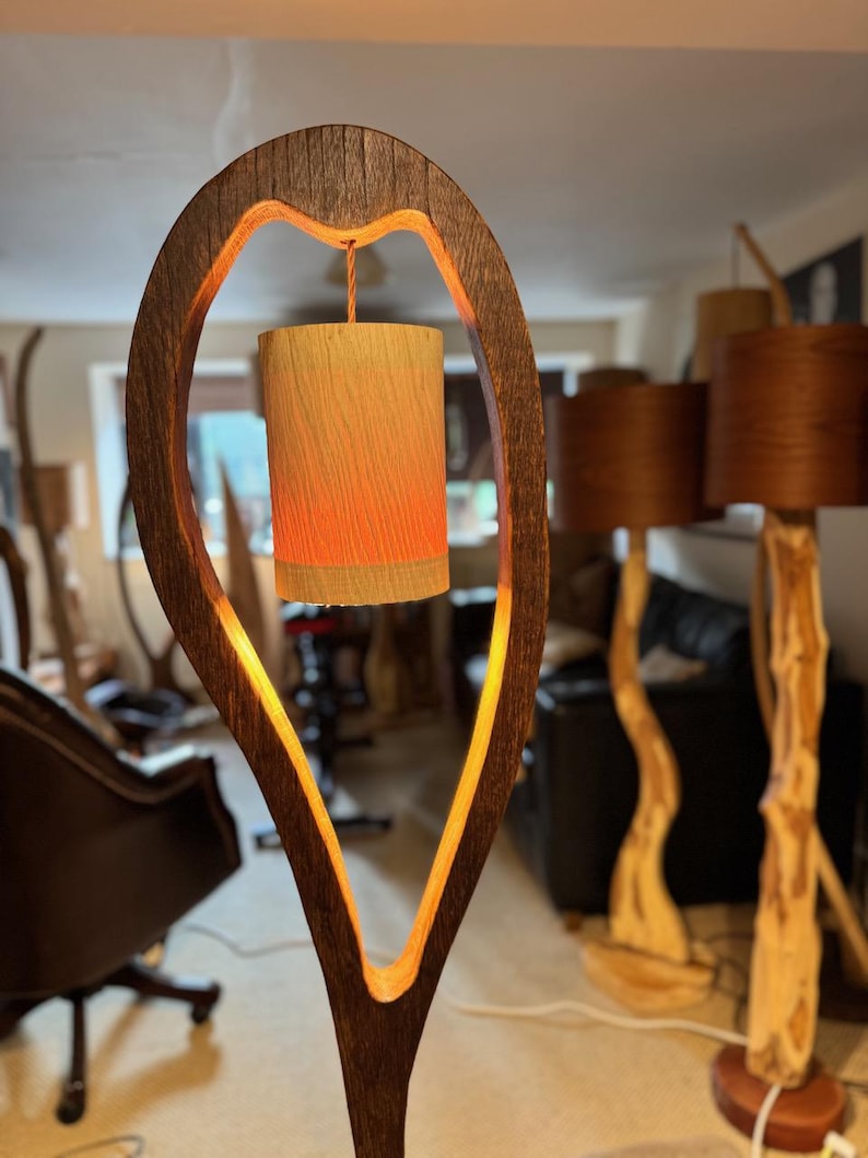 May include: A wooden lamp with a unique, heart-shaped design. The lamp features a warm, glowing light emanating from a cylindrical shade.