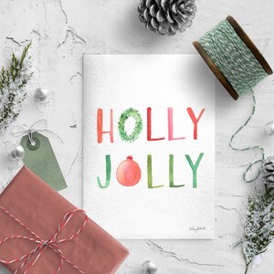 May include: A watercolor Christmas card with the words "HOLLY JOLLY" in green, red, and pink. The "O" in "HOLLY" is a green wreath and the "O" in "JOLLY" is a red ornament.