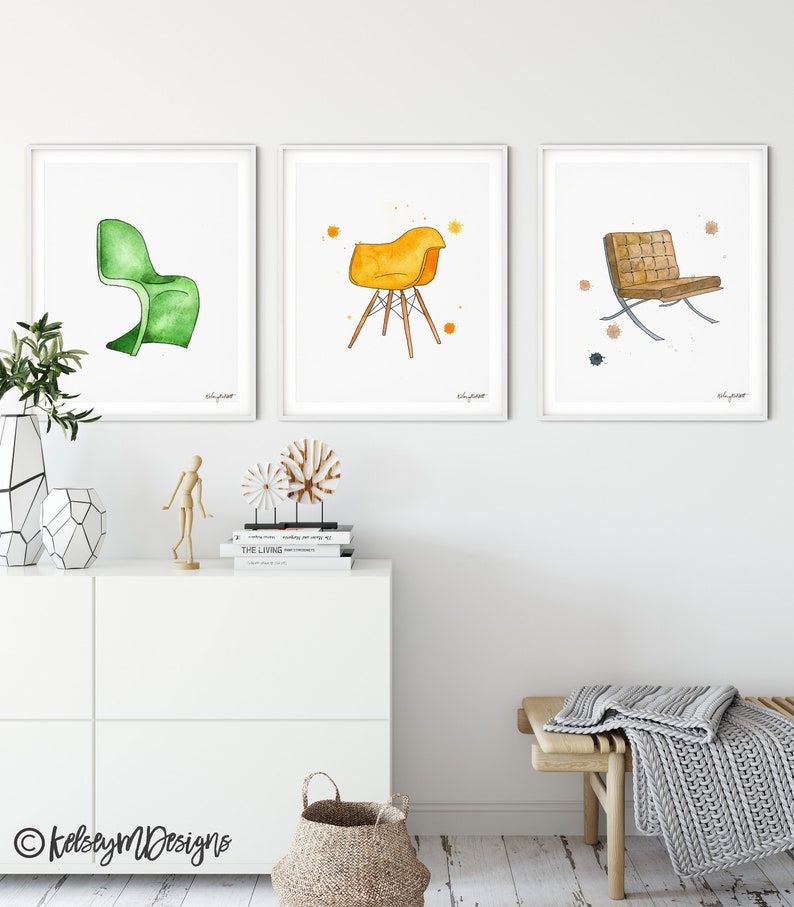 May include: Three watercolor illustrations of chairs, each framed in white. The first chair is green and has a curved back. The second chair is yellow and has a four-legged base. The third chair is brown and has a metal frame.