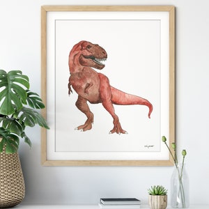 May include: Watercolor painting of a Tyrannosaurus Rex in shades of red and brown, framed in a light wood frame. The dinosaur is depicted in a side profile, with its mouth open. The artwork is signed by the artist.