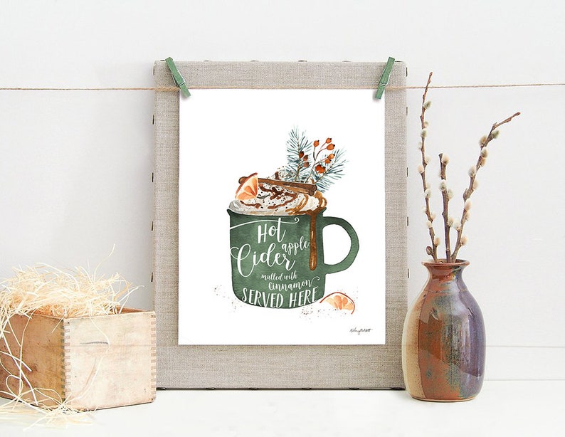 May include: A watercolor illustration of a green mug filled with hot apple cider, topped with whipped cream, cinnamon sticks, and an orange slice. The text reads "Hot apple cider, mulled with cinnamon, served here."