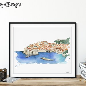 May include: Watercolor painting of a city on a peninsula with a blue ocean surrounding it. The city is made up of many buildings with red tile roofs. The painting is framed in a black frame.