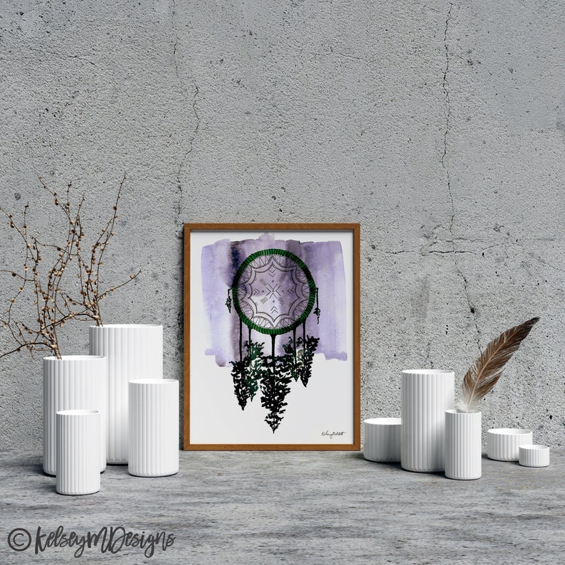 May include: A framed watercolor print of a purple and green dreamcatcher with a white background. The dreamcatcher is hanging from a green branch with a white background. The print is framed in a brown wood frame.