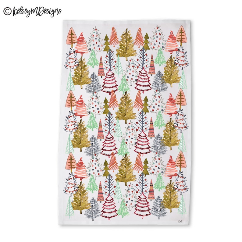 May include: White rectangular kitchen towel with a repeating pattern of stylized Christmas trees in various colors. The trees are in shades of red, green, gold, and gray, with some decorated with ornaments. The towel has the text "KelseyMDesigns" in the upper left corner.