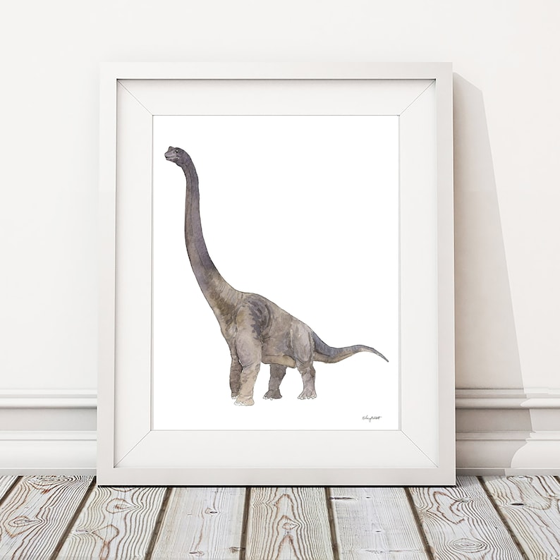 May include: A framed watercolor print of a Brachiosaurus dinosaur. The artwork features a long-necked dinosaur in shades of gray and brown against a white background. The print is displayed in a white frame, suitable for nursery or children's room decor.