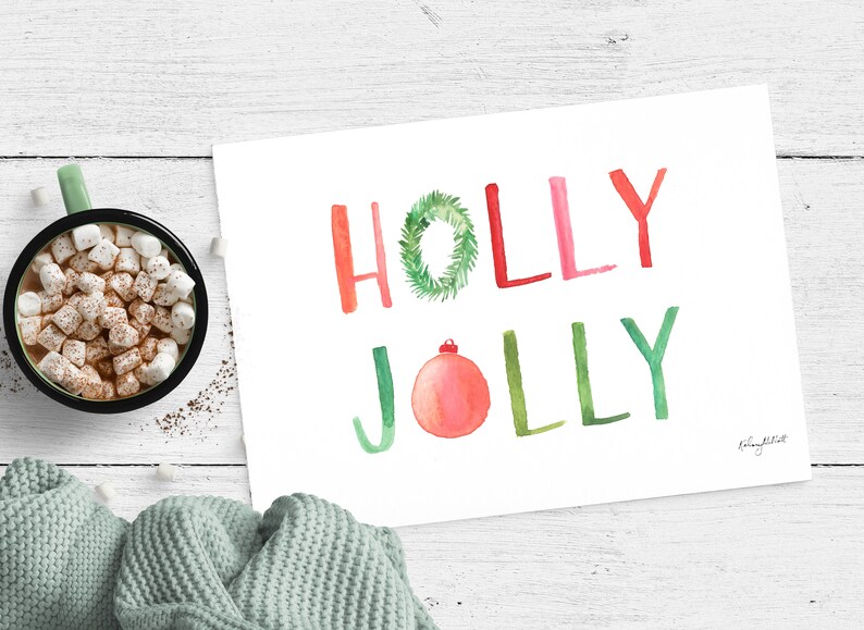 May include: A white card with the words "HOLLY JOLLY" written in red, green, and pink watercolor. A green holly wreath is incorporated into the word "HOLLY". A red and pink ornament is incorporated into the word "JOLLY".