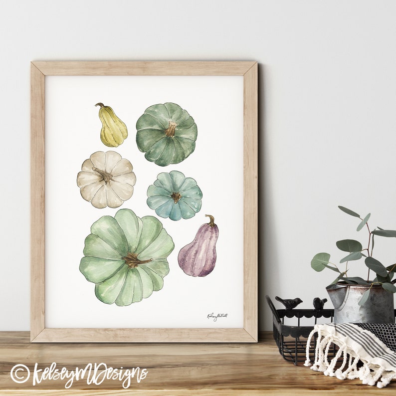 May include: A watercolor painting of gourds and pumpkins in various shades of green, blue, yellow, and purple. The gourds and pumpkins are arranged in a cluster on a white background. The painting is signed "kelsey m. platt" in the bottom right corner.