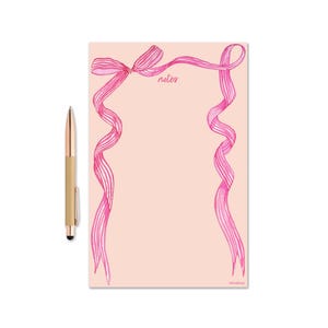 Può includere: Blocco note rosa con un bordo di nastro rosa e la parola "notes" al centro.