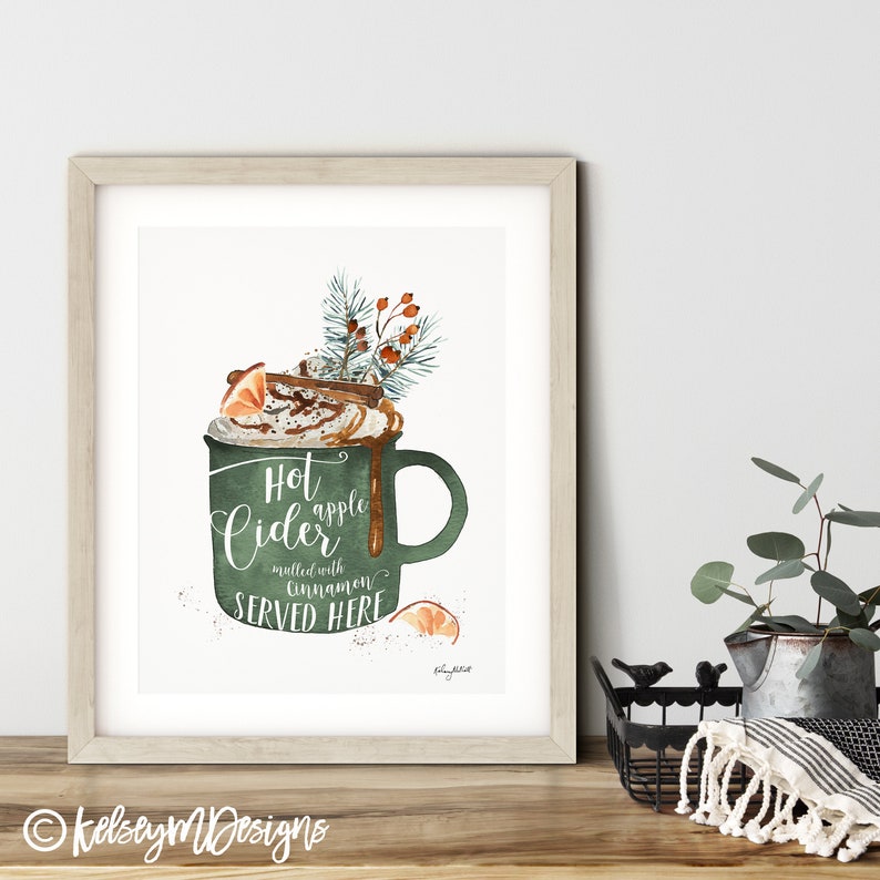 May include: A watercolor illustration of a green mug filled with hot apple cider topped with whipped cream, cinnamon sticks, and a slice of orange. The text reads "Hot apple cider mulled with cinnamon SERVED HERE".