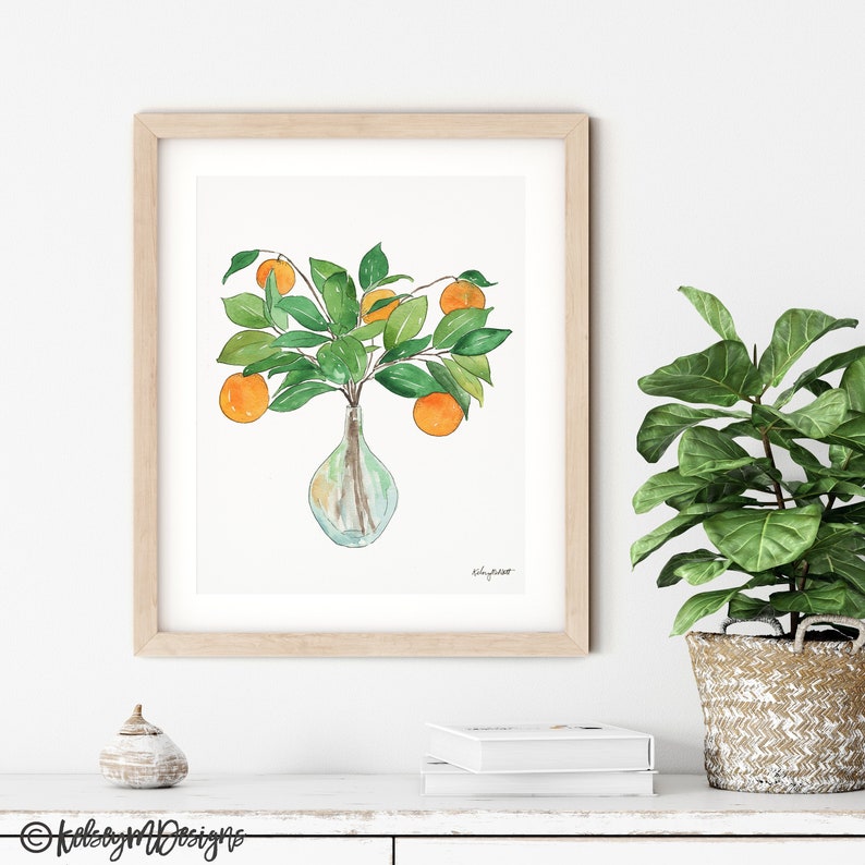 May include: Watercolor painting of a vase with orange fruit and green leaves. The vase is clear glass and the fruit is a bright orange color. The leaves are a deep green color. The painting is framed in a light wood frame.
