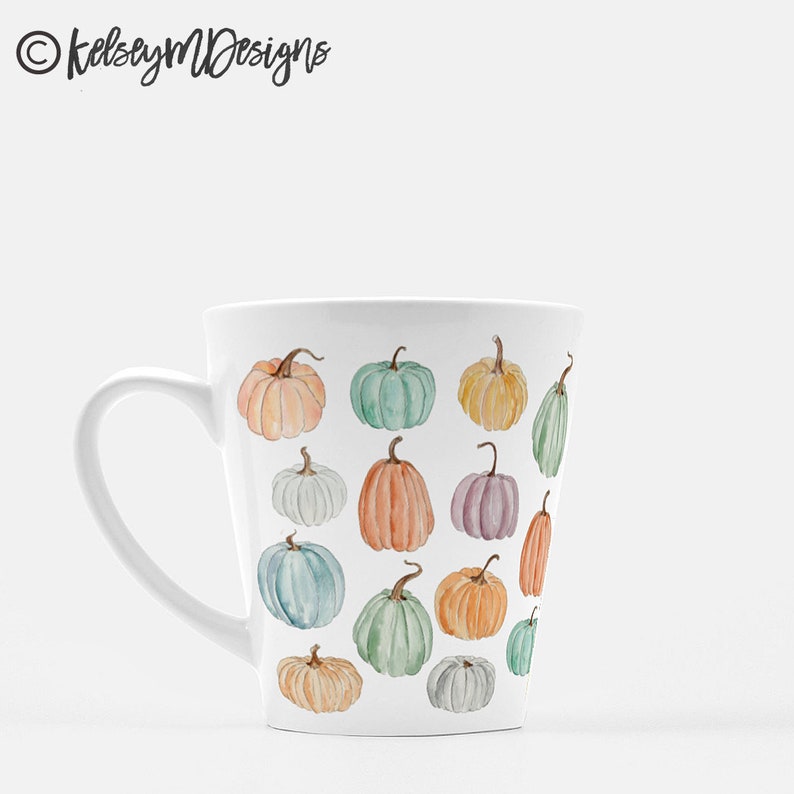 May include: White ceramic mug with a pattern of colorful pumpkins. The mug has a handle and a tapered shape.