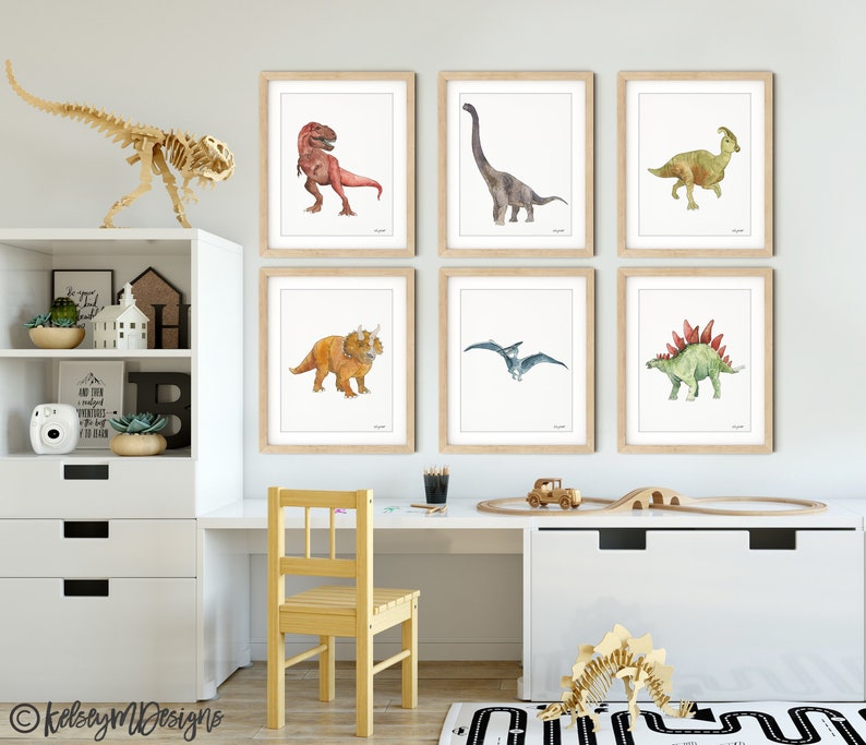 May include: Watercolor dinosaur art prints in wooden frames, including a T-Rex, Brontosaurus, Triceratops, Pterodactyl, and Stegosaurus. A wooden dinosaur skeleton and a child's desk with a chair are also visible.