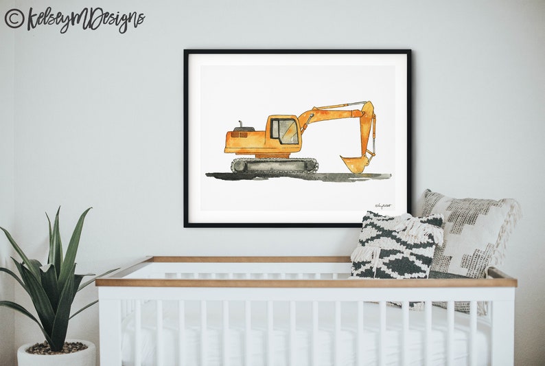 May include: Watercolor painting of an orange excavator in a black frame. The construction vehicle is depicted on a white background. The artwork is displayed above a white crib with a plant and decorative pillows.