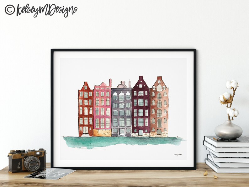 May include: Watercolor painting of a row of five colorful buildings with windows and doors. The buildings are painted in shades of red, pink, purple, brown, and gray. The buildings are set against a light blue background with a green waterline at the bottom.