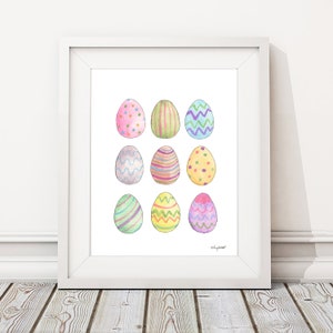 May include: A white frame containing a white background with nine colourful Easter eggs, each with a different pattern. The eggs are arranged in three rows of three. The eggs are painted in shades of pink, blue, green, yellow, and purple.