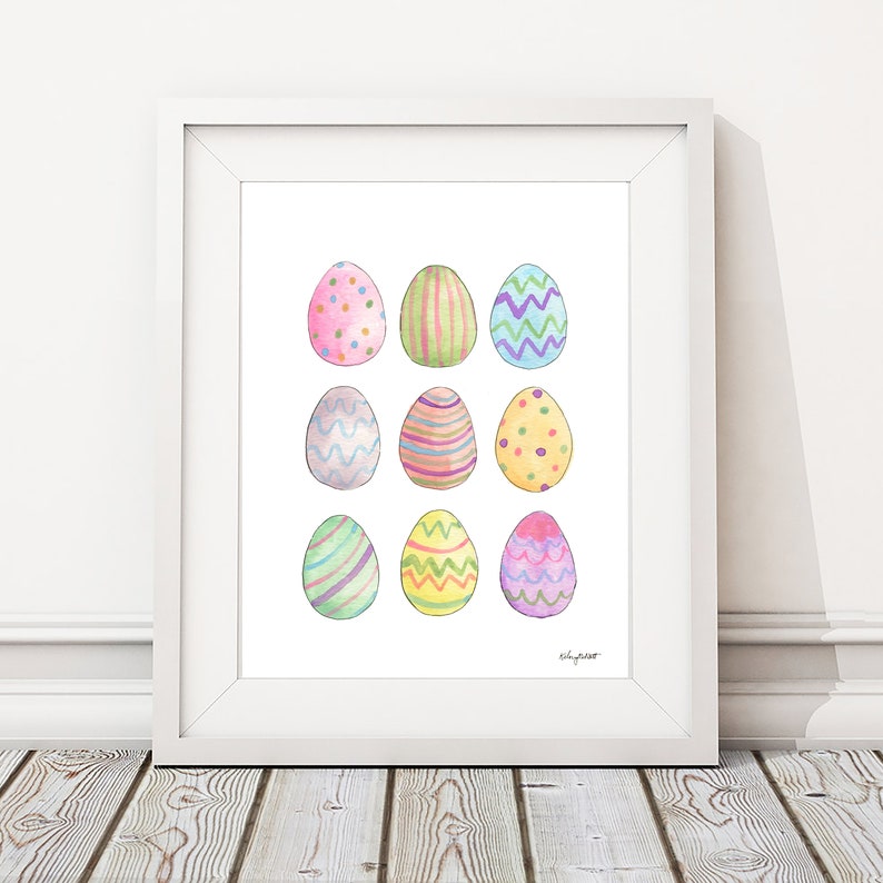 May include: A white frame containing a white background with nine colourful Easter eggs, each with a different pattern. The eggs are arranged in three rows of three. The eggs are painted in shades of pink, blue, green, yellow, and purple.