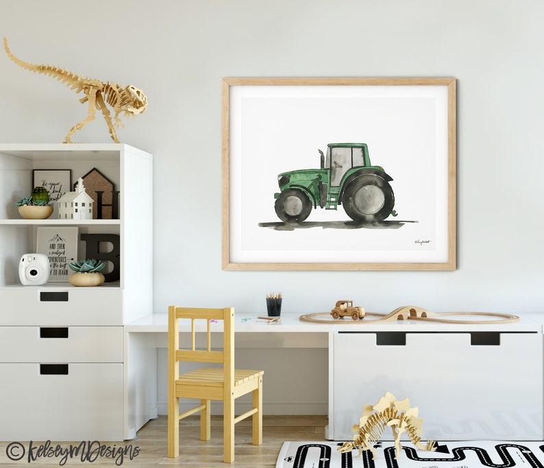 May include: A watercolor painting of a green tractor on a white background. The tractor is in profile view and has a black tire on the left side and a gray tire on the right side. The painting is framed in a light wood frame.
