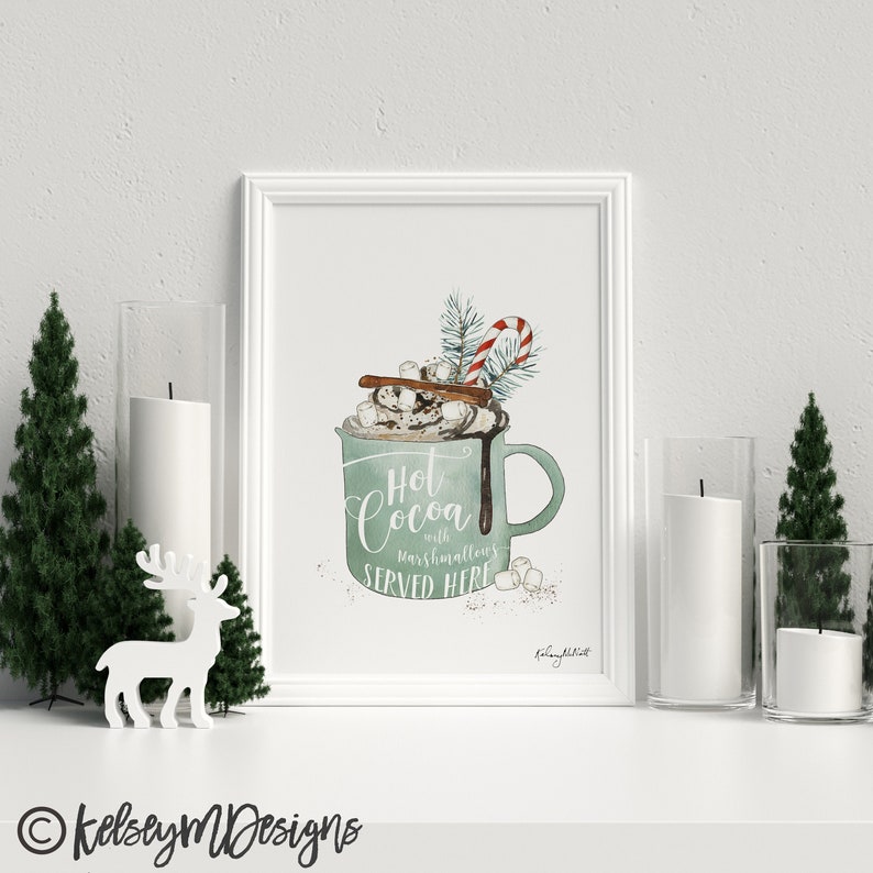 Puede incluir: Una ilustraci&oacute;n de acuarela de una taza verde llena de chocolate caliente, cubierta con crema batida, malvaviscos, un palo de canela y un bast&oacute;n de caramelo. El texto dice "Chocolate caliente con malvaviscos SERVIDO AQU&Iacute;".