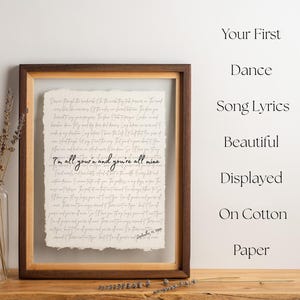 Puede incluir: Una impresión enmarcada con letras de canciones en papel de algodón. El texto "I'm all yours and you're all mine" es visible. El marco es marrón con un borde interior claro. Un jarrón de lavanda seca está a la izquierda.