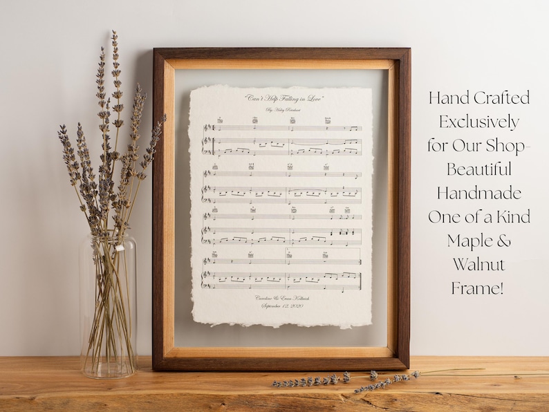 Peut inclure: Une partition encadr&eacute;e intitul&eacute;e Can't Help Falling in Love avec un bord effiloch&eacute;, dans un cadre en bois d'&eacute;rable et de noyer bicolore. L'impression pr&eacute;sente des notes de musique et du texte. Un vase en verre transparent contient de la lavande.