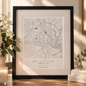 May include: A framed map print of Charleston, South Carolina, featuring black road lines on a light gray background with a red heart icon. The text reads Where We Said I Do, September 22, 2022, and Charleston, SC, in a black serif and script font.