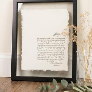 May include: A framed artwork featuring a handwritten script on textured paper. The black frame surrounds the paper, which has a deckled edge. The text includes the words "All Yours". The artwork is displayed on a wooden surface.
