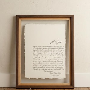 May include: A framed handwritten letter with the words "All Yoed" at the top. The letter is on a cream-colored paper with a deckled edge, set within a wooden frame. The frame is a warm brown color, and the background is a neutral beige.