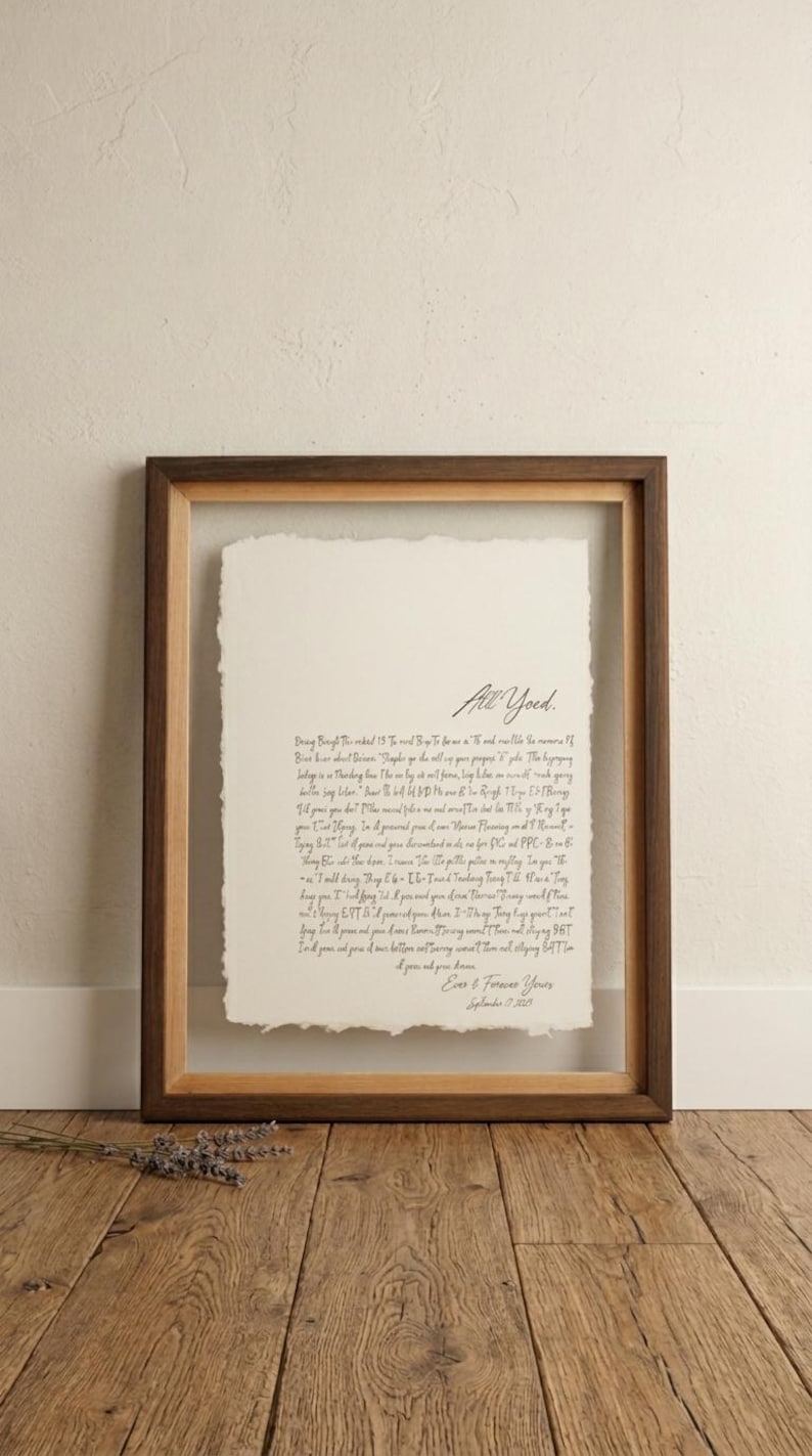 May include: A framed handwritten letter with the words "All Yoed" at the top. The letter is on a cream-colored paper with a deckled edge, set within a wooden frame. The frame is a warm brown color, and the background is a neutral beige.