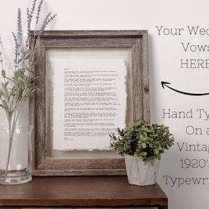 May include: A framed piece of paper with typed text, a bouquet of lavender in a clear glass vase, and a small potted plant in a white pot. The text on the paper reads "Your Wedding Vows HERE! Hand Typed On a Vintage 1920's Typewriter".