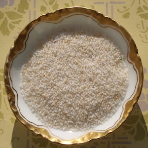 May include: A white porcelain dish with a gold rim, filled with a large quantity of small, white, round beads.