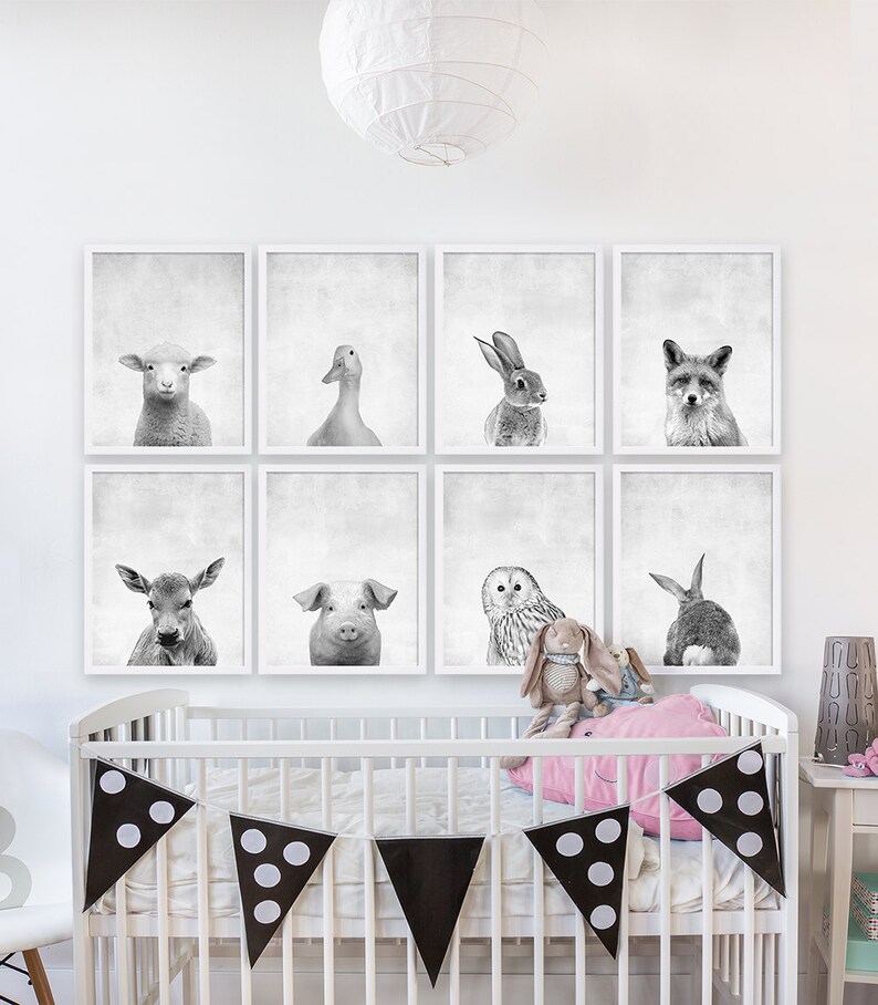 Puede incluir: Un conjunto de seis estampados de animales en blanco y negro en marcos blancos. Los estampados representan una oveja, un pato, un conejo, un zorro, un ciervo, un cerdo, un b&uacute;ho y un conejo. Los estampados est&aacute;n dispuestos en forma de cuadr&iacute;cula en una pared blanca sobre una cuna blanca con una almohada rosa y ropa de cama de lunares blancos y negros.