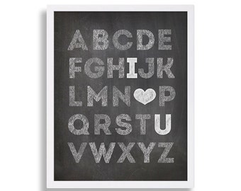 May include: Black chalkboard with white chalk lettering spelling out the alphabet. The letter "I" is followed by a heart symbol and the letter "U".
