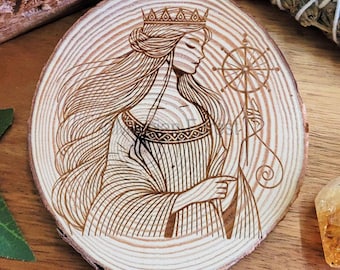 Könnte beinhalten: Ein Holzbranddesign einer Frau mit Krone, die ein Spinnrad auf einem Holzuntersetzer hält.