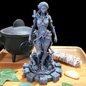 May include: A grey, matte-finished figurine of a standing female figure with long hair, wearing a top and skirt with vine-like details. The figure stands on a circular base with square blocks featuring spiral symbols, surrounded by a small owl and foliage.