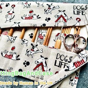 Op de afbeelding: Een beige stoffen breinaaldenetui met een hondenpatroon, met houten naalden, een haaknaald en een schaar. De etui heeft de tekst "DOGS LIFE" en "KnittingBagAndCase".