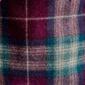 May include: A woven fabric featuring a plaid pattern with intersecting lines in shades of deep magenta, dark purple, teal, and white. The material has a soft, slightly fuzzy texture with a visible weave throughout the entire surface area.