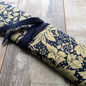 May include: A gold and navy blue fabric roll with a floral pattern, tied with a navy blue ribbon.