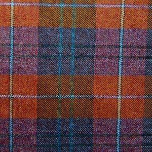 May include: A woven fabric featuring a plaid pattern with intersecting lines in shades of burnt orange, deep purple, and dark blue. The textile displays a diagonal twill weave texture with thin, light-colored vertical and horizontal stripes.