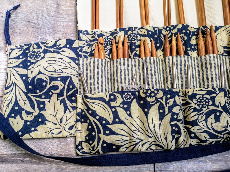 May include: A blue and gold fabric roll-up case with a black strap. The case has multiple pockets for storing knitting needles. The label on the case reads "Wakari Aki".