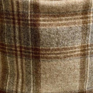 May include: A woven fabric featuring a classic plaid pattern in shades of tan, brown, and gray. The material has a soft, textured appearance with intersecting horizontal and vertical lines forming a grid across the surface of the textile.