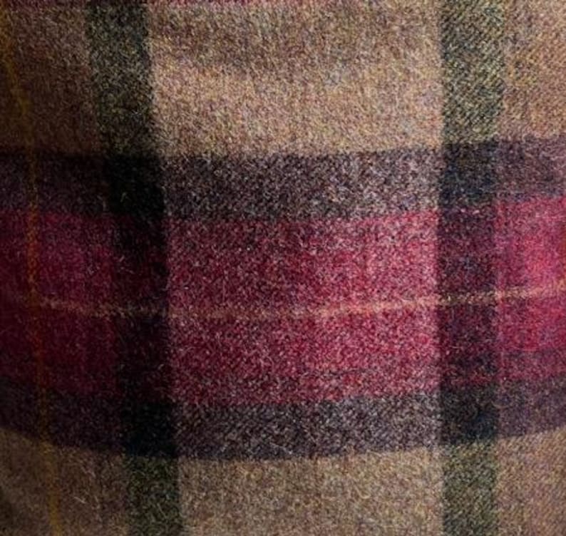 May include: A textured fabric featuring a plaid pattern with intersecting lines in shades of tan, deep burgundy, and dark charcoal gray. The material has a visible woven wool-like consistency with a soft, slightly fuzzy surface finish.