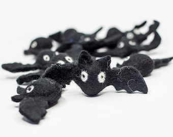 May include: A group of black felt bats with white eyes. The bats are arranged in a line, with the largest bat in the front.
